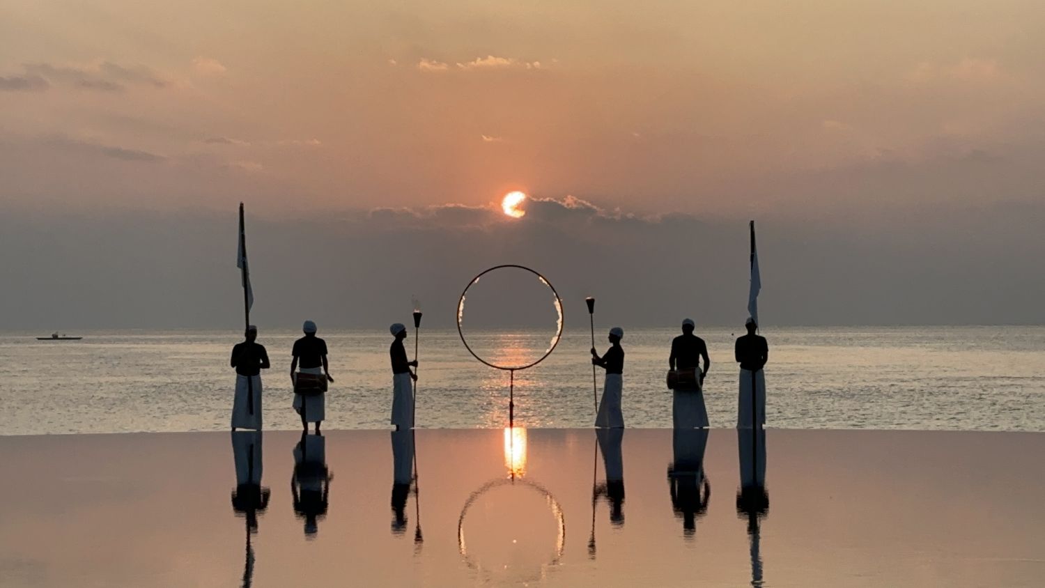 Sunset drumming ceremony reflected on an infinity pool in the Maldives